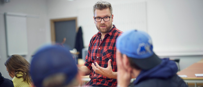 Lärare vid whiteboard och elever vid ett skrivbord.